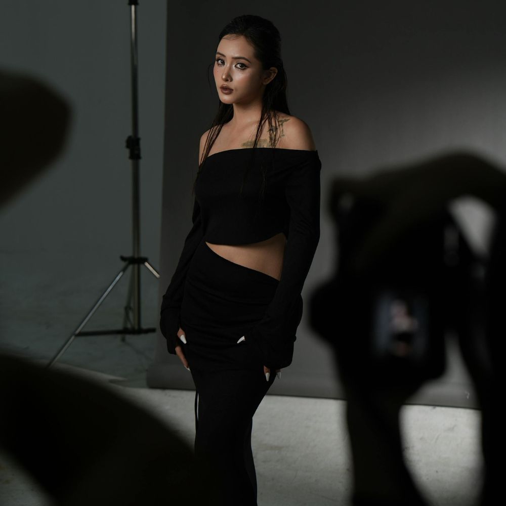 Séance photo de mode en studio, modèle posant devant le fond et photographe au premier plan