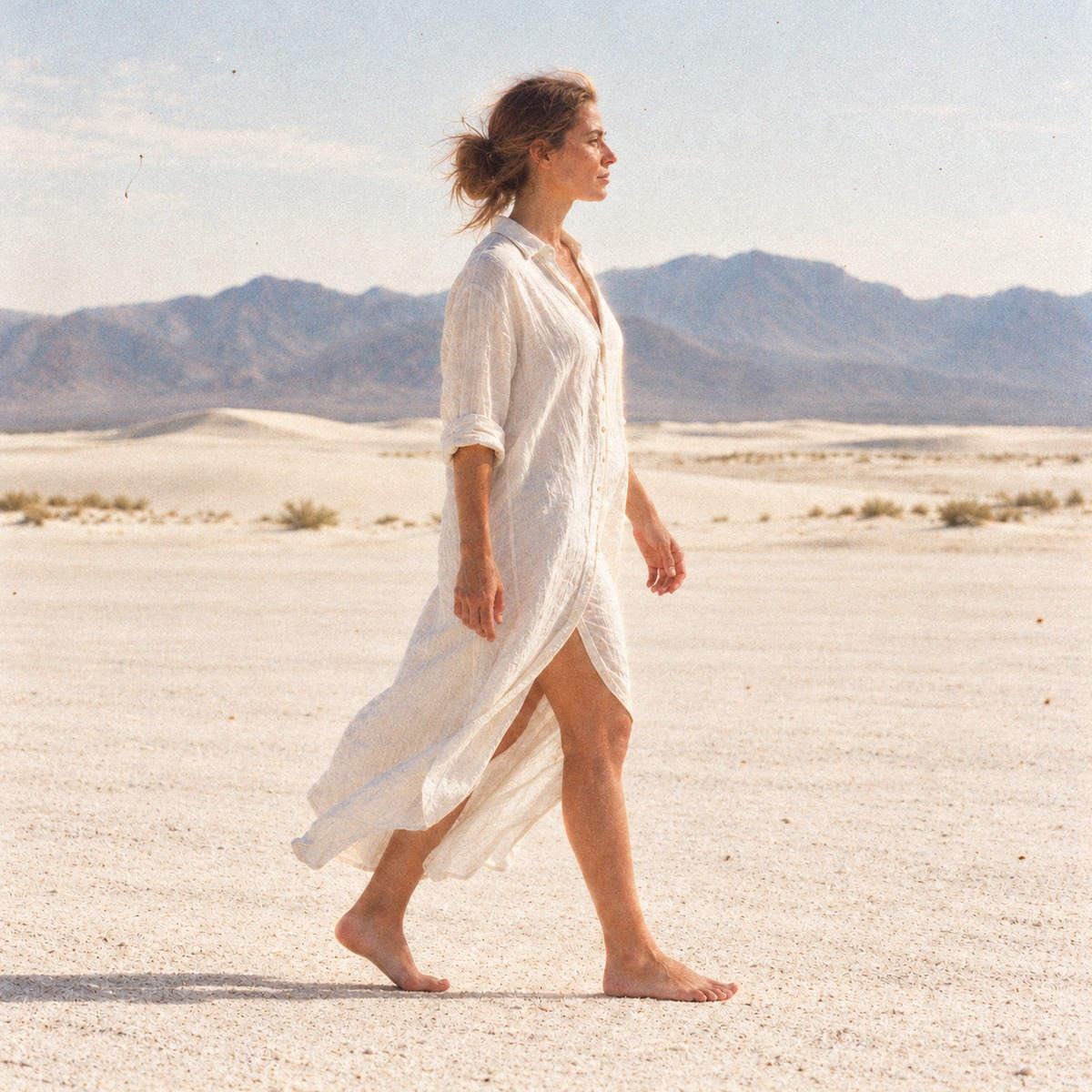 Mannequin pieds nus en robe chemise blanche marchant devant la toile de fond photo paysage naturel Désert blanc, shooting de mode en studio