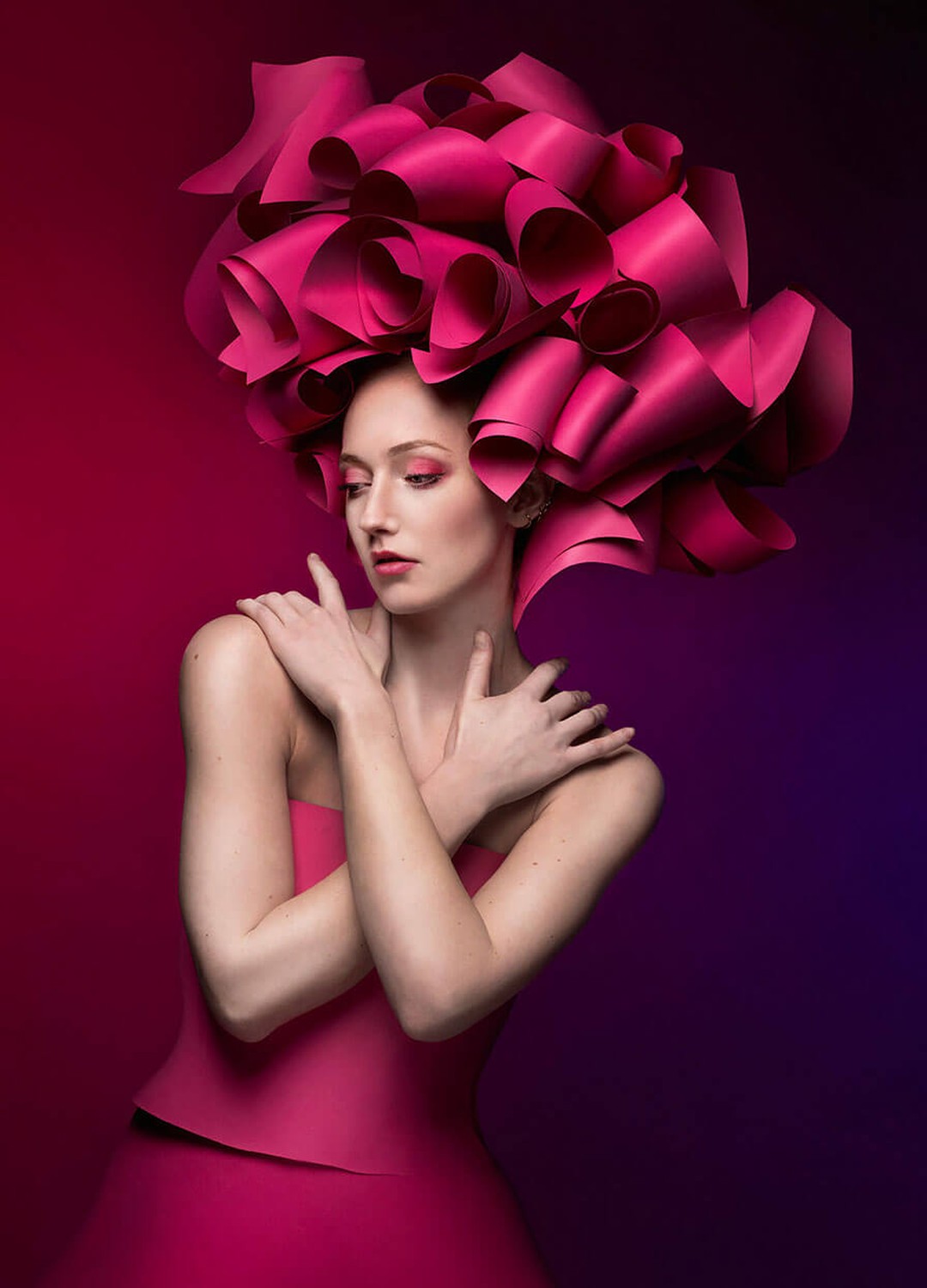 Portrait mode en studio d'un modèle à la coiffe en papier rose, éclairé au flash Elinchrom