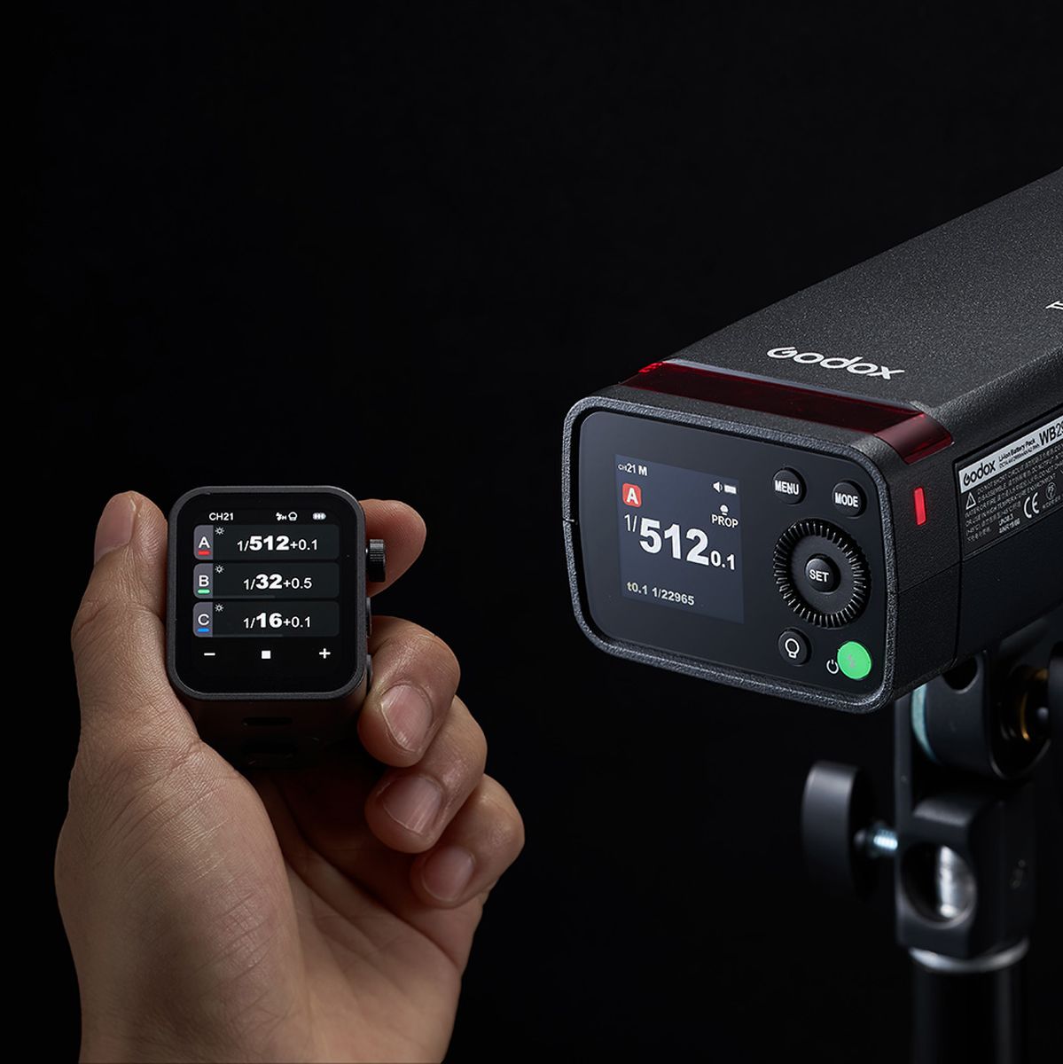 Écran couleur du flash portable Godox AD200Pro II sur un pied, piloté par un transmetteur Godox tenu en main