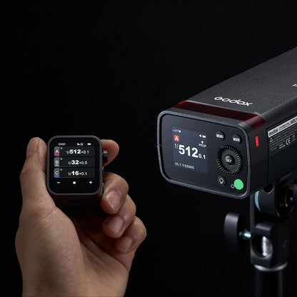 Écran couleur du flash portable Godox AD200Pro II sur un pied, piloté par un transmetteur Godox tenu en main