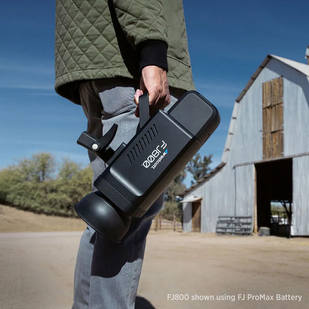 Flash Westcott FJ800 porté par sa poignée en extérieur, avec batterie FJ ProMax