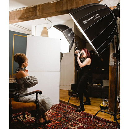 Séance portrait en intérieur éclairée par deux boîtes à lumière Elinchrom, photographe face à une modèle assise