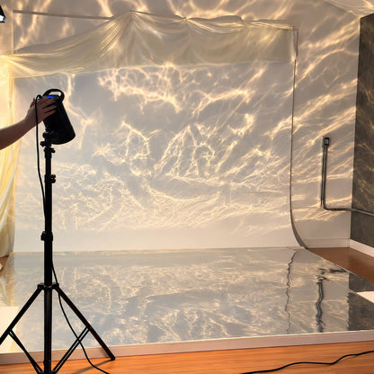 Fond photo métallique posé au sol en studio, face argent, reflets de lumière effet eau projetés sur le mur