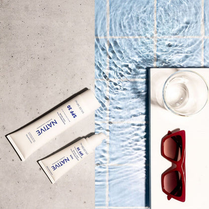 Flat lay réalisé avec l'Aqua Tray, tubes de crème solaire et lunettes au bord d'une surface d'eau